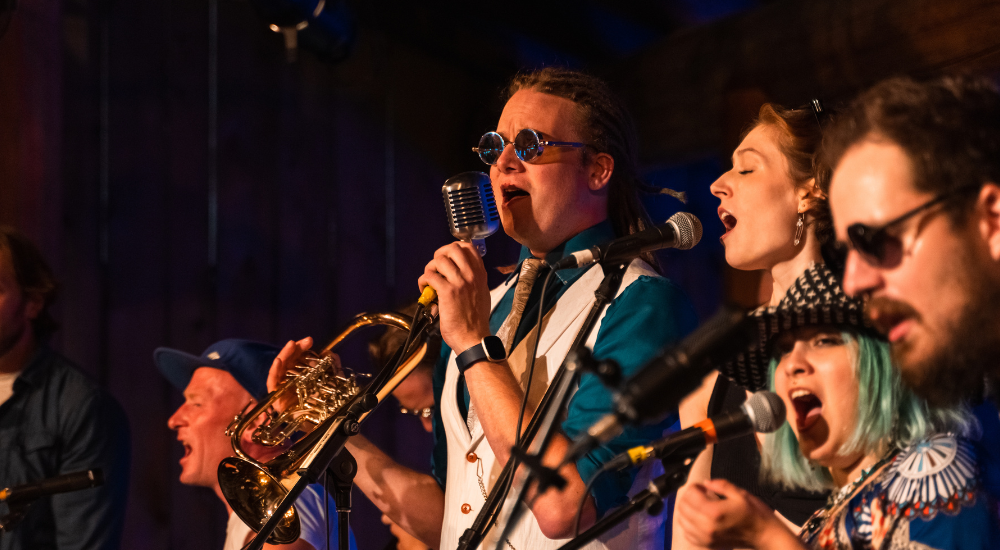 Side view of several performers singing into mics.
